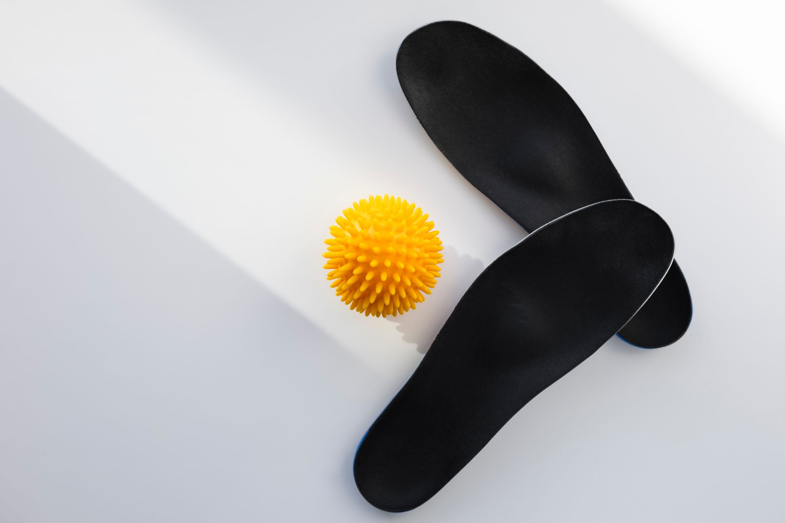 A pair of XO-SOLEs next to a yellow massage roller.