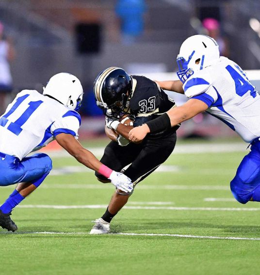 Football Players Making a Tackle A football player prepares to be tackled by two opponents.