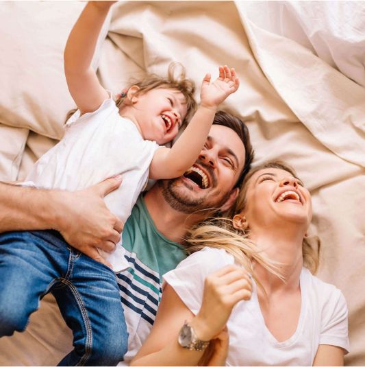 Family Laughing Together A family laughing together on a bed.