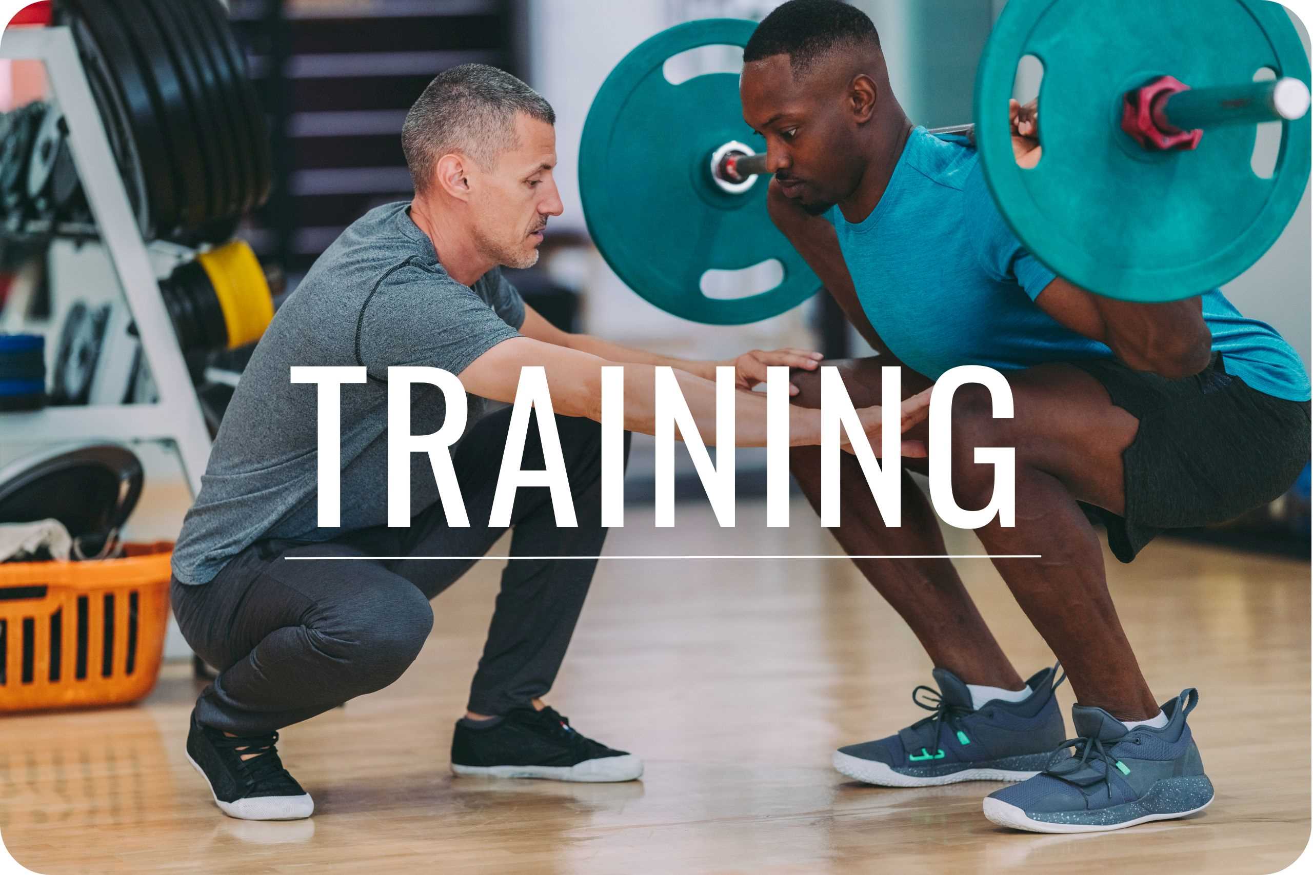Training A fitness trainer assisting an athlete during a back squat.