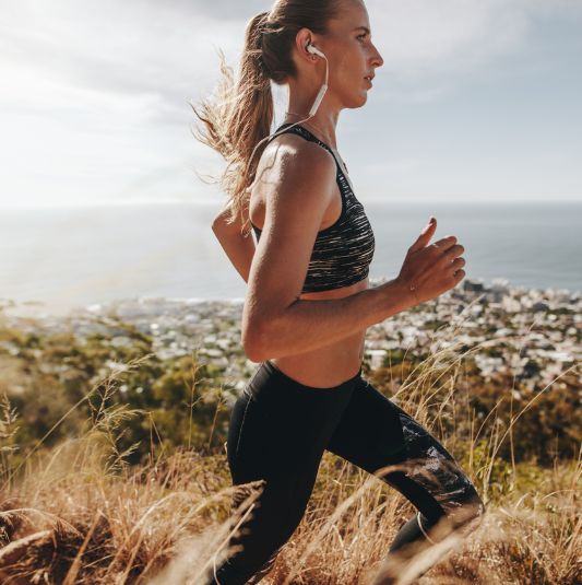 Female athlete running on a trail overlooking the city.