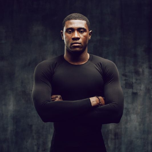Male athlete standing with arms folded.