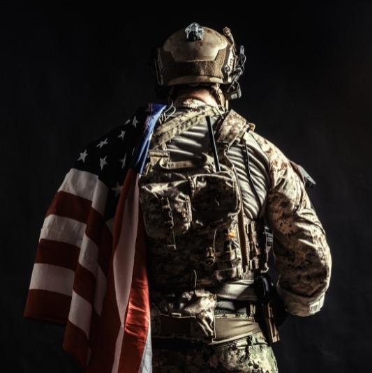 Military Service A member of the U.S. Military with an American Flag draped on their shoulder.